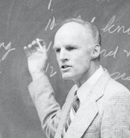 Truman Madsen teaching at a chalkboard.