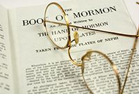 A pair of glasses sitting atop an open Book of Mormon.