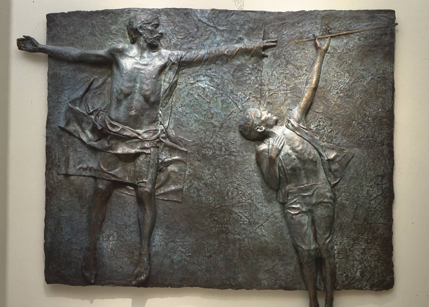 A metal art piece depicting a boy reaching out to an iron rod, with help from Jesus Christ