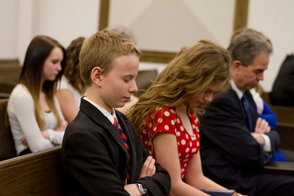 A family sitting in a church pew in prayer