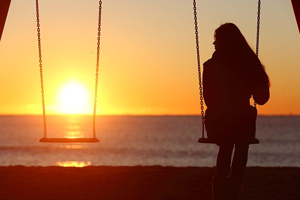 Woman on a swing at the beach during sunset